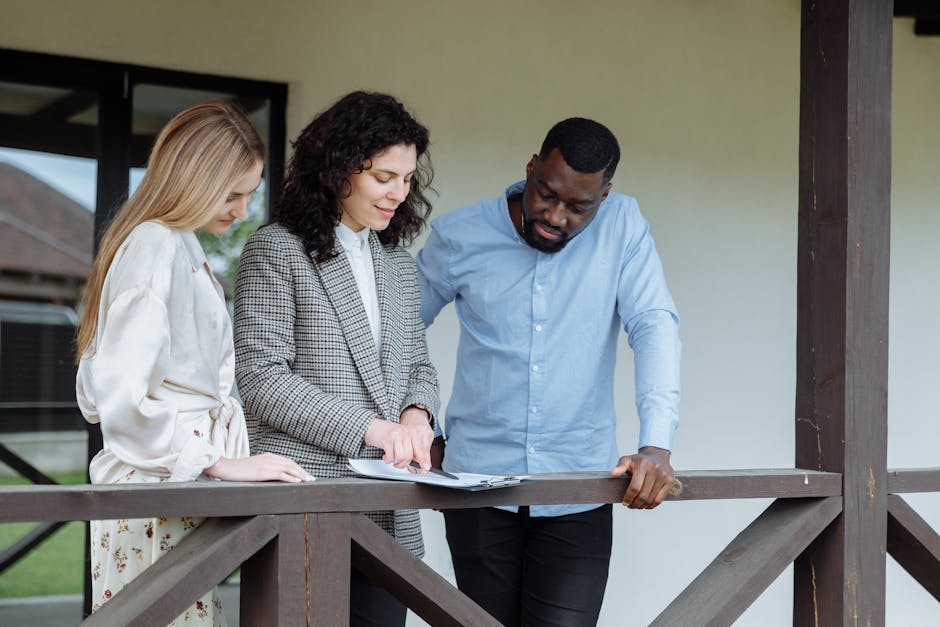 Real estate agent discussing property paperwork with a couple on a porch.