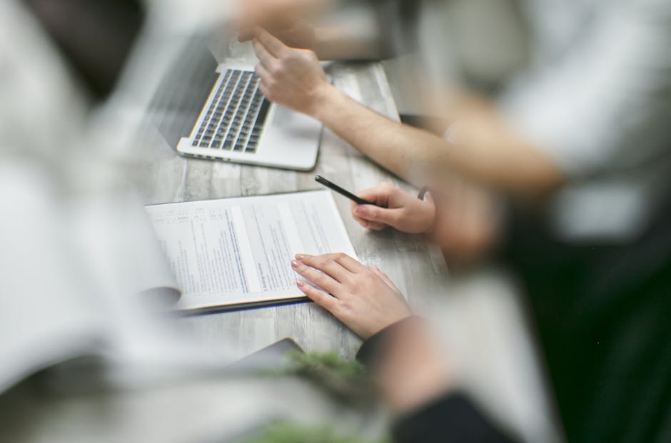 Close-up view of a team collaborating with documents and a laptop in an office setting.